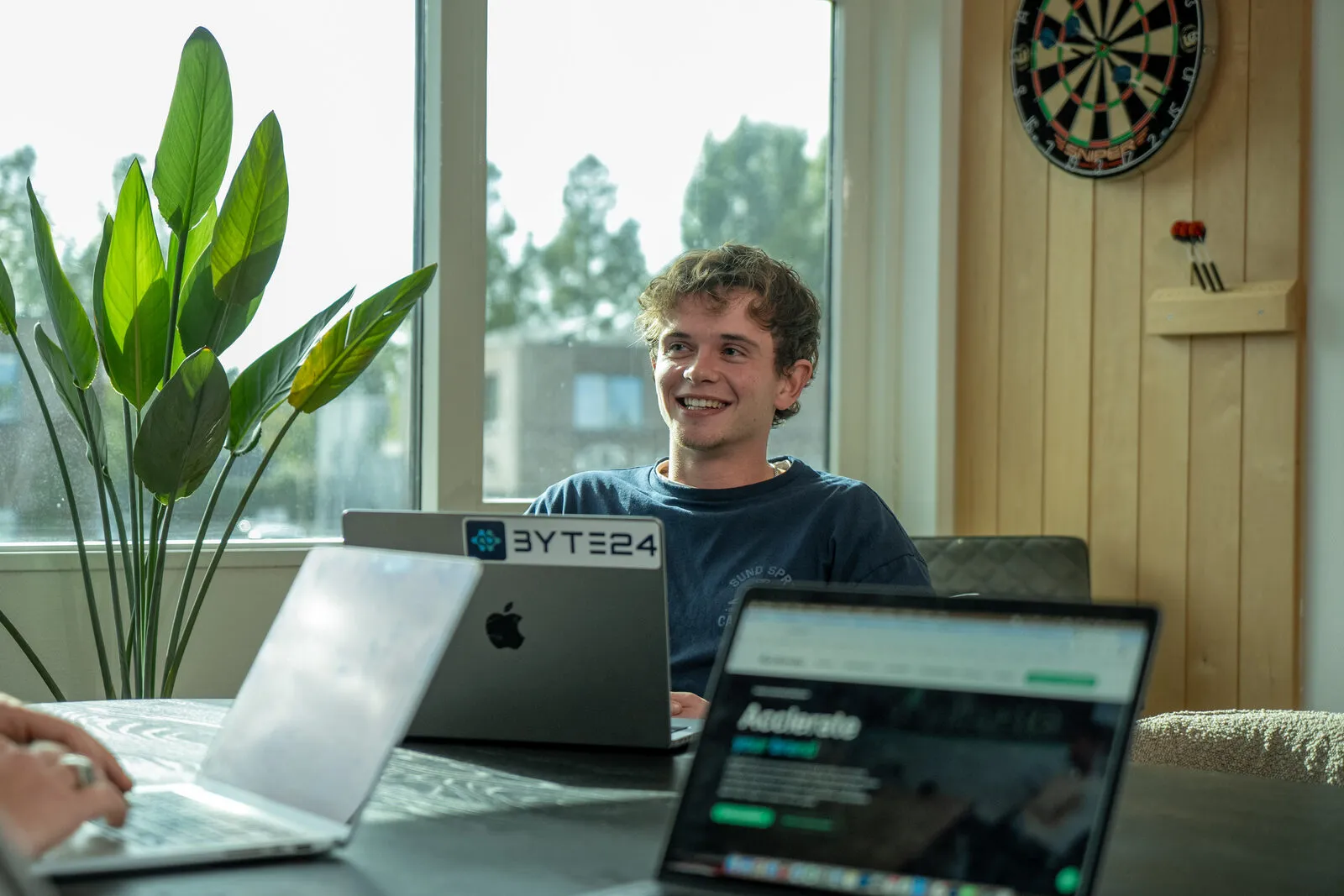 Collega's van Acclerate overleggen aan tafel met hun laptops